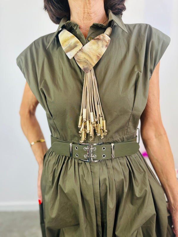 Person wearing an olive green dress with a unique collar design and belt.